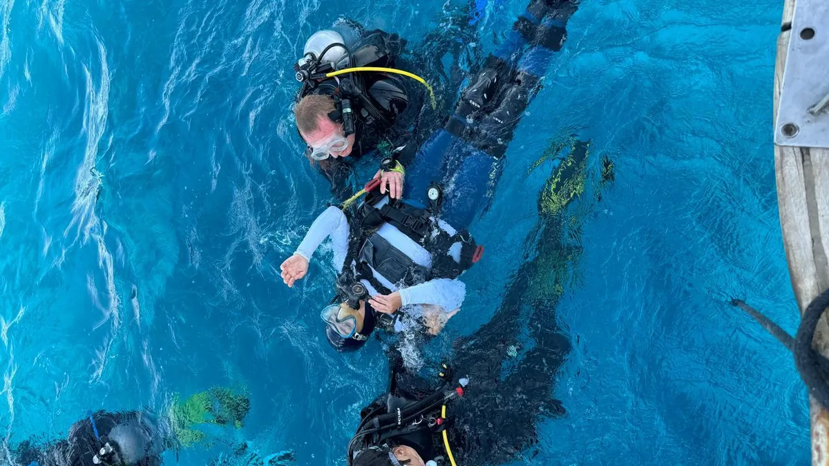 An adaptive diver hovering weightless and relaxed in clear blue water, an instructor close beside them