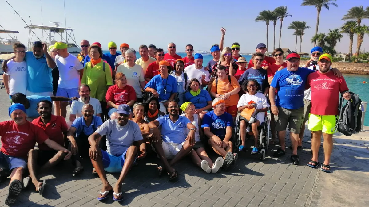 A small, smiling group on a dive boat including an adaptive diver and their companions, sharing the day together