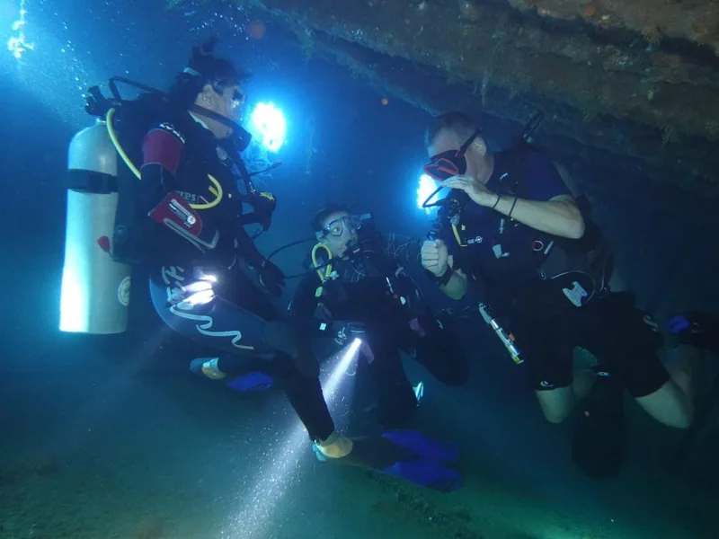 A diver inside one of the Abu Nuhas wrecks, light streaming through the broken hull, northern Red Sea