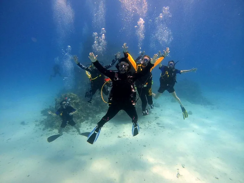 A group of scuba divers hovering over a Red Sea reef with arms outstretched
