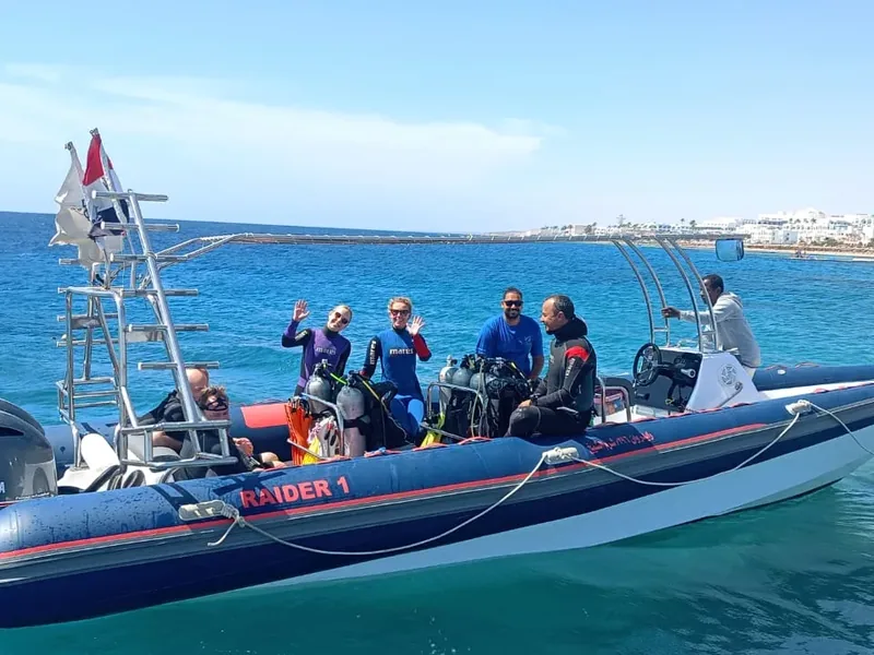Scuba divers and a dive boat over a Red Sea reef in Egypt — planning a diving trip budget