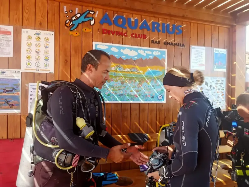 A dive guide's save-a-dive kit laid out on a boat deck — spare O-rings, mask and fin straps, mouthpiece, zip ties, silicone grease and a multi-tool